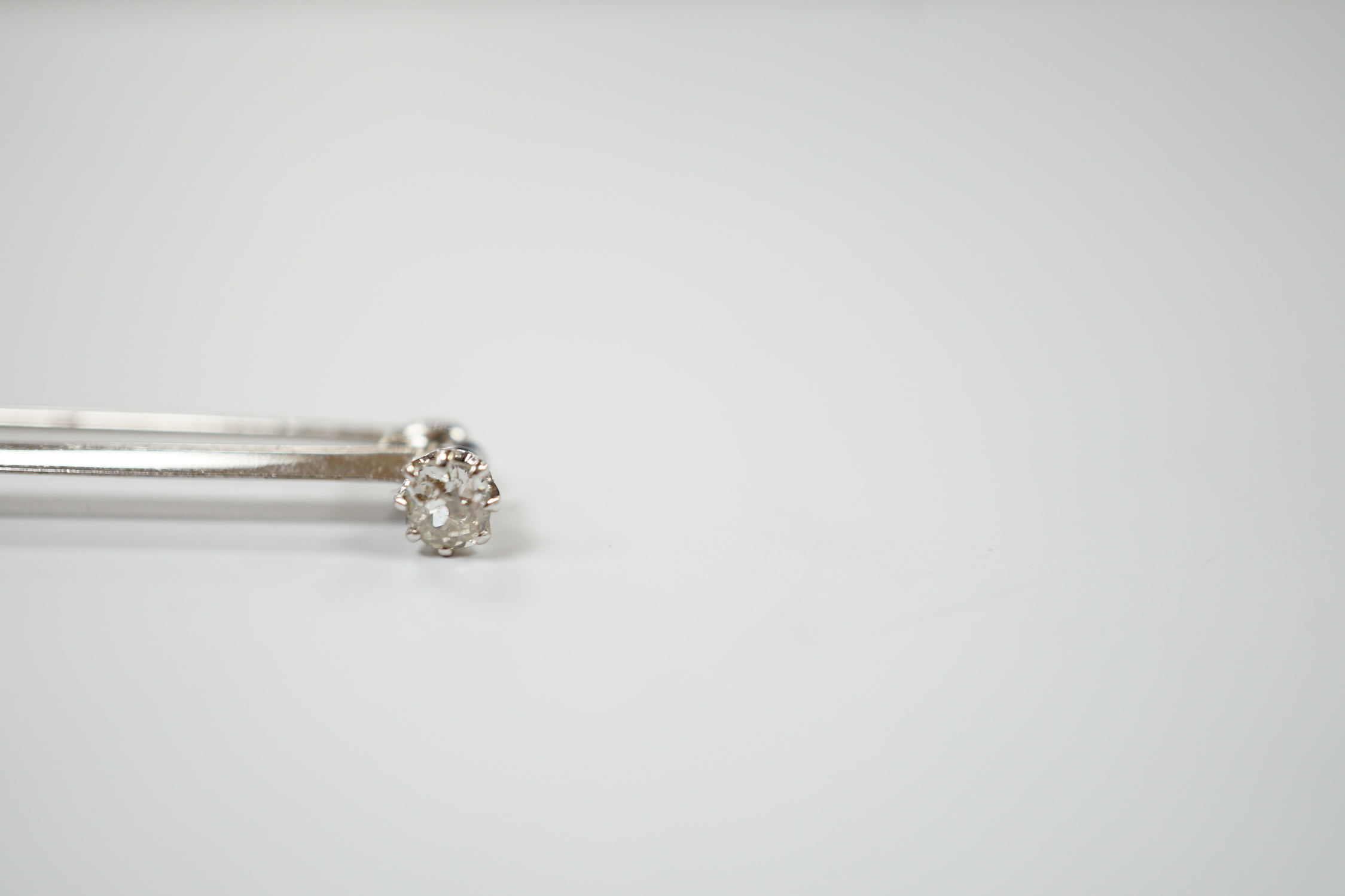 A white metal and three stone diamond set bar brooch, 56mm, gross weight 3.4 grams.